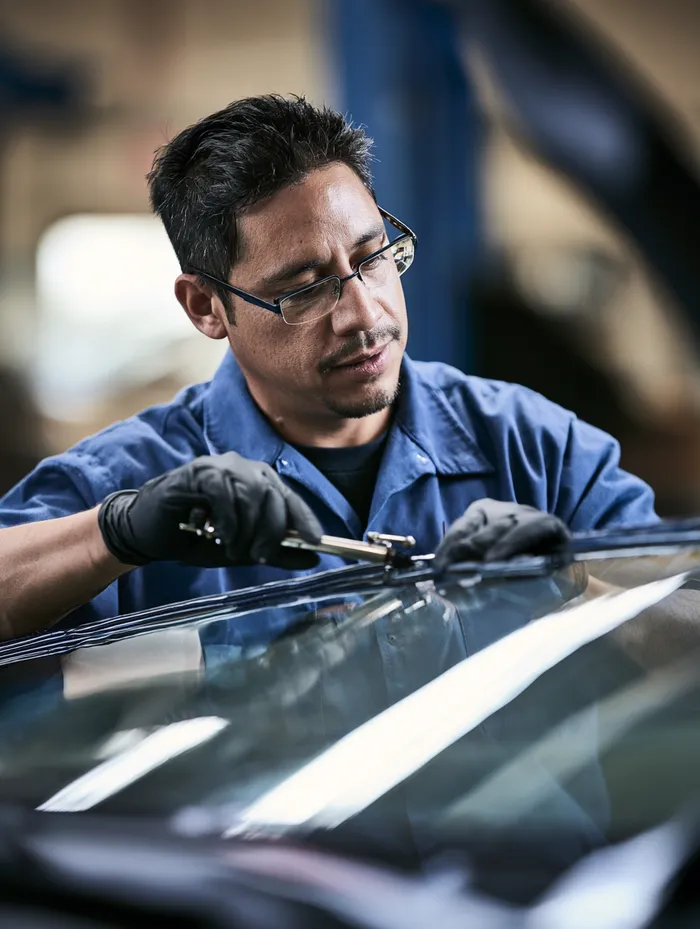 Glass technician applying a urethane bead around a windshield frame with steady hands